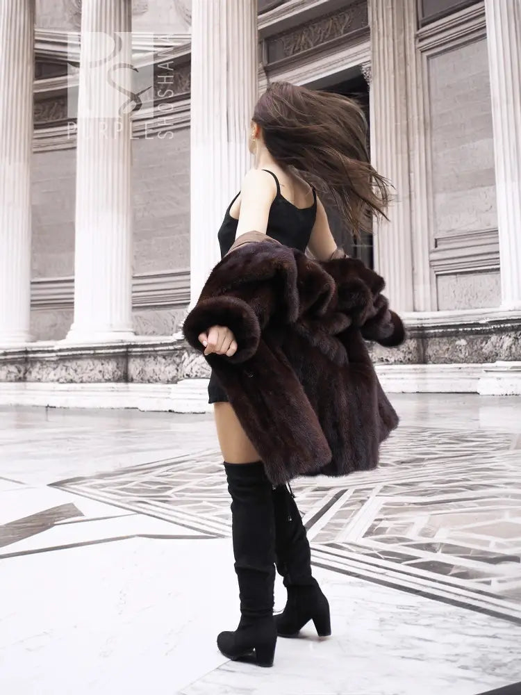 Dark brown mink fur coat with wide collar and cropped sleeves over black dress