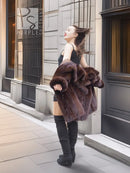 Dark brown fur coat with wide collar and flared sleeves, worn with dark knee boots.