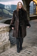 Long dark mink coat with front buttons, plush fur cuffs, and structured sheared sleeves