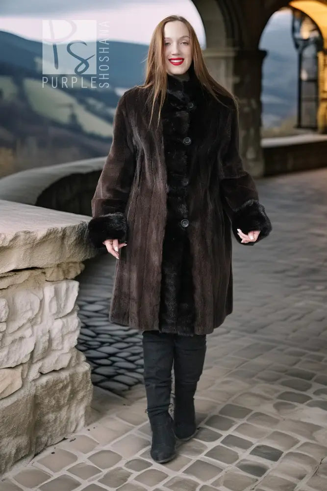 Long dark mink coat with front buttons, plush fur cuffs, and structured sheared sleeves