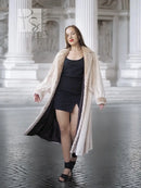 Cream beaver fur coat worn open over a black dress, with notched collar and long sleeves