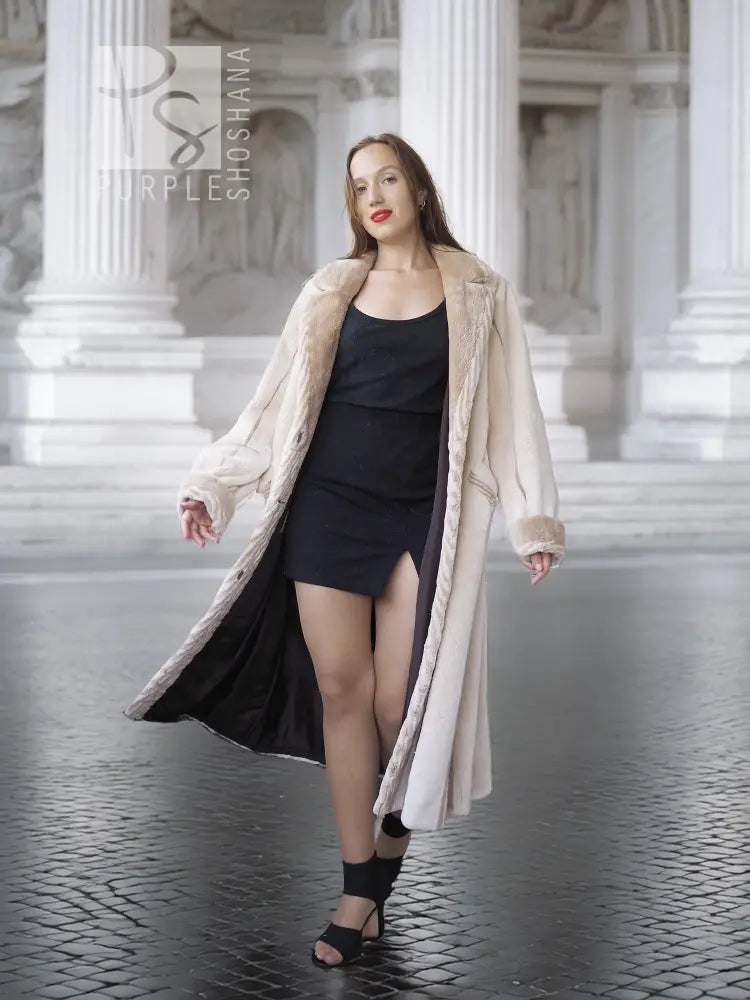 Cream beaver fur coat worn open over a black dress, with notched collar and long sleeves