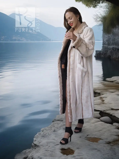 Cream beaver fur coat with buttonless open front and long sleeves.