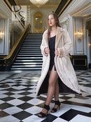 Cream fur coat with open front and shawl collar; long knee-to-mid-calf length.