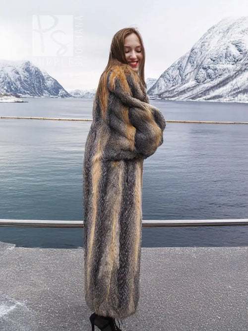 Three-quarter view of gray and amber fox fur coat with long sleeves and straight hem.