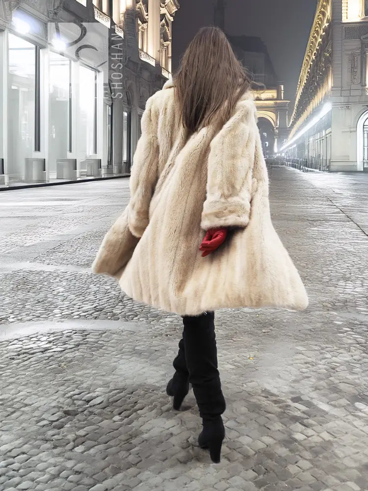 Beige mink fur coat in back view with flared hem and red glove accents