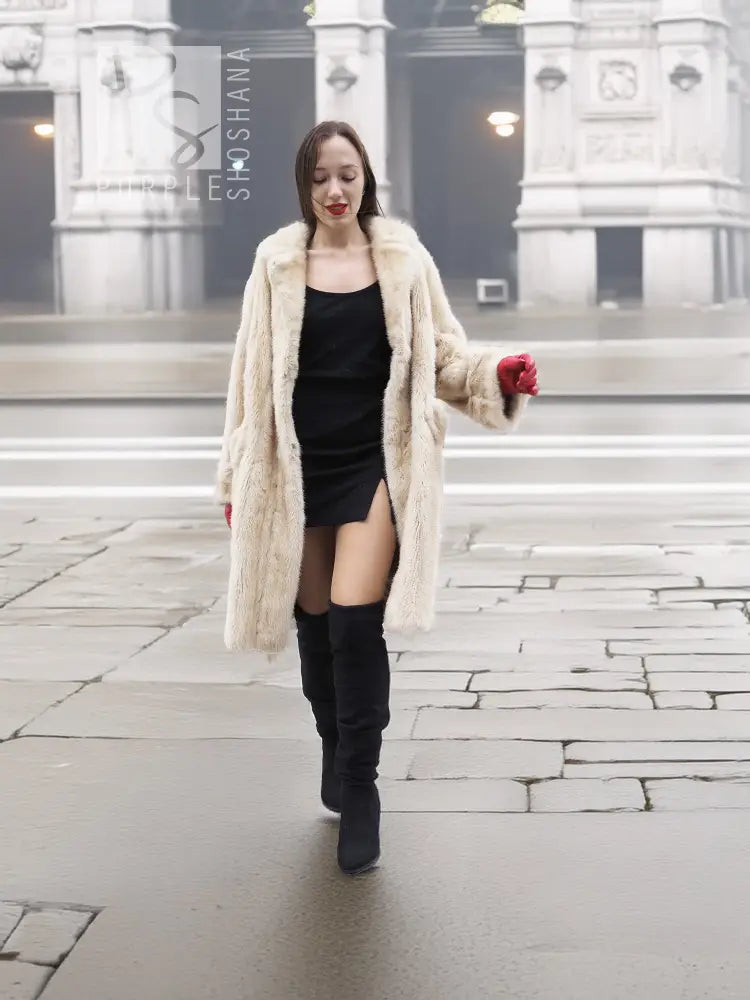 Beige mink fur coat with open front and long sleeves, worn with red gloves