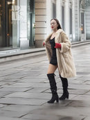 Beige mink fur coat with open collar and long sleeves, styled with black boots