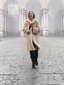 Beige mink fur coat in front view with open collar and red gloves