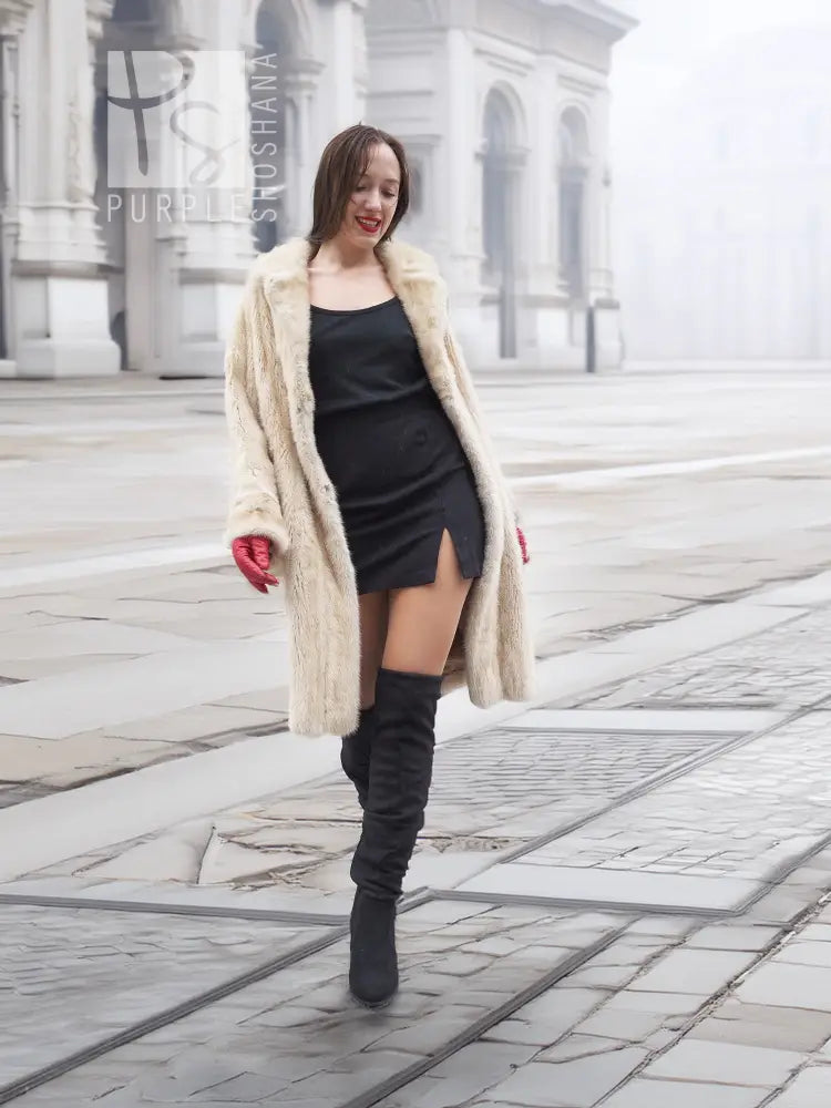 Beige mink fur coat worn over black dress, open front with plush beige fur