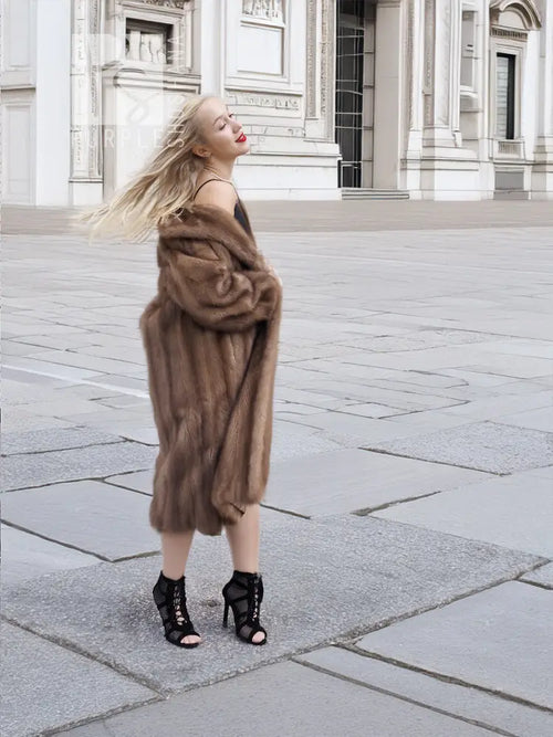 Brown mink fur coat in side profile, shawl-style collar and knee-length hem