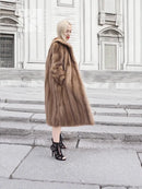 Brown mink fur coat with long straight silhouette and plush fur collar, side view