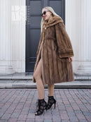 Brown mink fur coat with hood, mid-calf length, side pockets, relaxed fit.