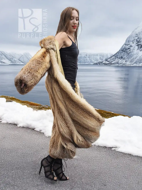 Long tan fur coat with open front; side view with one sleeve extended outward.