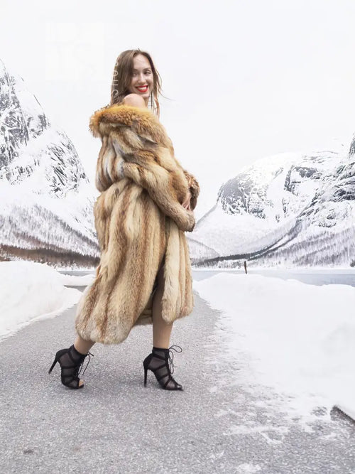 Long tan fur coat with open front; back/side view with fur collar and hood-like neckline.