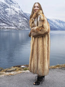 Long tan fur coat with open front; model facing camera, arms crossed over chest.