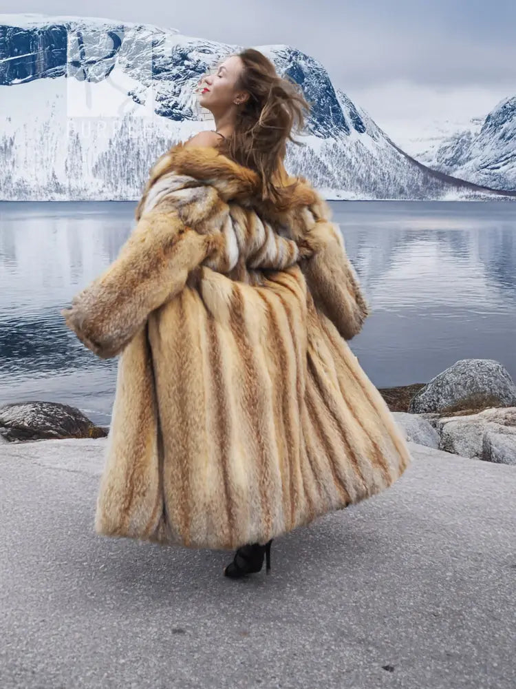 Long tan fur coat, open front; model in three-quarter back view, fur drape visible.