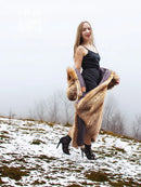 Tan fur coat with open front and bold fur trim over a dark inner dress.