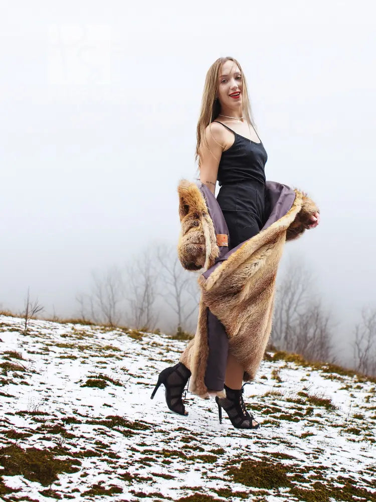 Tan fur coat with open front and bold fur trim over a dark inner dress.