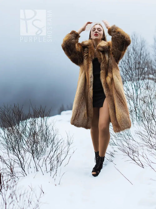 Tan fur coat with hood-like collar and open neckline over dark dress.