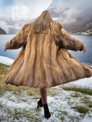 Tan fur coat with flared skirt hem and wide, draped shoulders.