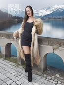 Tan faux fur coat with shawl collar and textured sleeves, standing pose beside stone walkway
